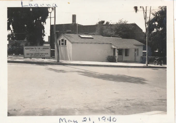 Black and white photo of Laguna Beach Library, exterior, May 21, 1940. Sign next to building reads: "Addition to the library Donated by the Members of the Building Contractor's Assn. of Laguna Beach"