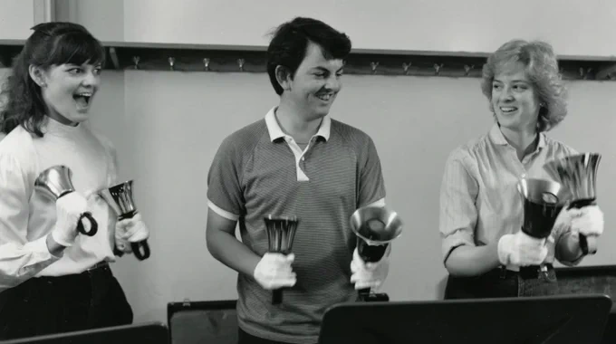 Three handbell players smiling while holding handbells