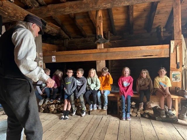 students sitting on a bench in a wood room at the forest history center