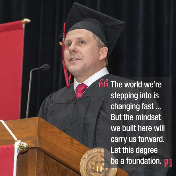 Graduate in cap and gown delivering a commencement speech at a podium with a motivational quote stating, The world we're stepping into is changing fast... But the mindset we built here will carry us forward. Let this degree be a foundation. 