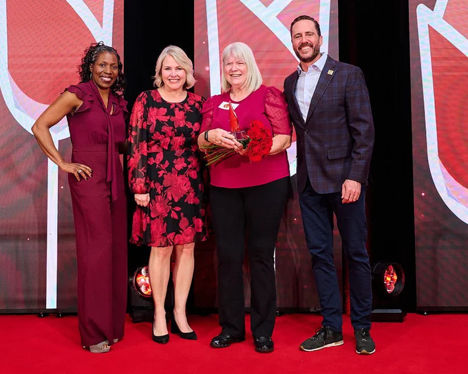 Boise State shuttle driver Denise Neilsen smiling during the 2026 ROSE (Recognition of Service Excellence) Award holding her trophy. 
