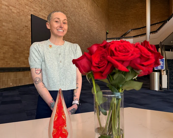 Morrison Center ticket operations supervisor Paige Thomas smiling next to her award and a vase of red roses. 
