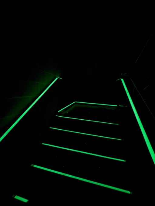Photograph of the same stairwell, luminous egress installed, showing stair landing perimeter markings and handrail and stair nosings. Copyright Luminous Egress.