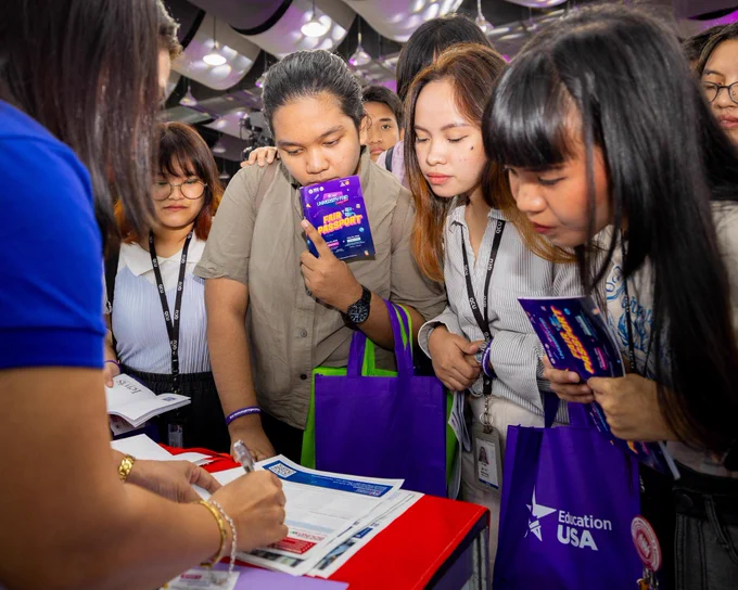 Students looking at a leaflet that a school representative is pointing to.