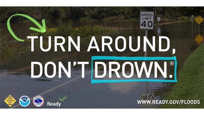 Flood water over a road and the message to turn around don't drown.