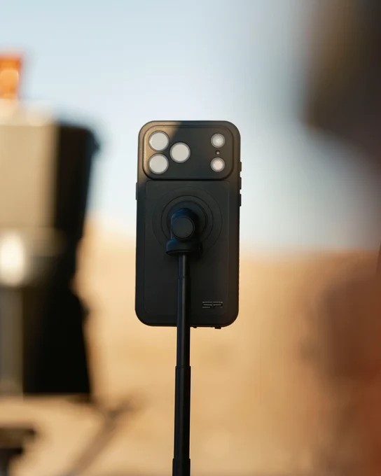 A black smartphone case with multiple camera lenses and a thumb control button attached to a black tripod.