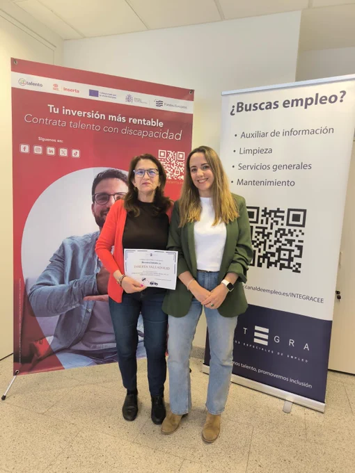 Dos personas posan juntas sosteniendo un diploma. Detrás, dos roll ups: uno de Inserta Empleo con el mensaje “Tu inversión más rentable. Contrata talento con discapacidad” y otro de Integra CEE con el encabezado “¿Buscas empleo?” y varias opciones de puestos de trabajo.