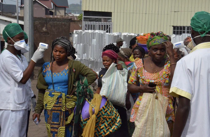 Healthcare workers in scrubs and masks screen women in the Democratic Republic of Congo for Ebola.