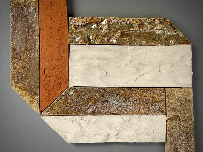 A clay tile with different colour brown, cream and orange glazes