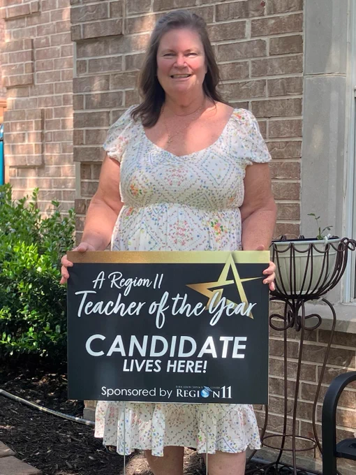 Mary McMinimy, Lewisville ISD and Flower Mound High School Secondary Teacher of the Year, standing outside house with a yard sign that reads, "A Region 11 Teacher of the Year Candidate Lives Here!" 