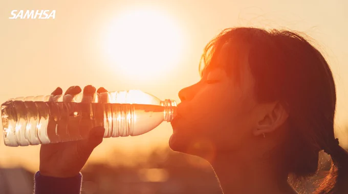A person is drinking from a water bottle outdoors at sunset, with the bright sun in the background. The SAMHSA logo is visible in the top left corner.