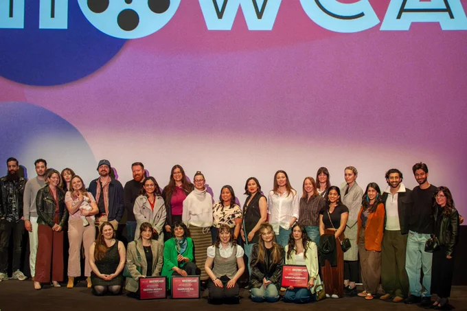 A group photo on stage with pink backdrop.