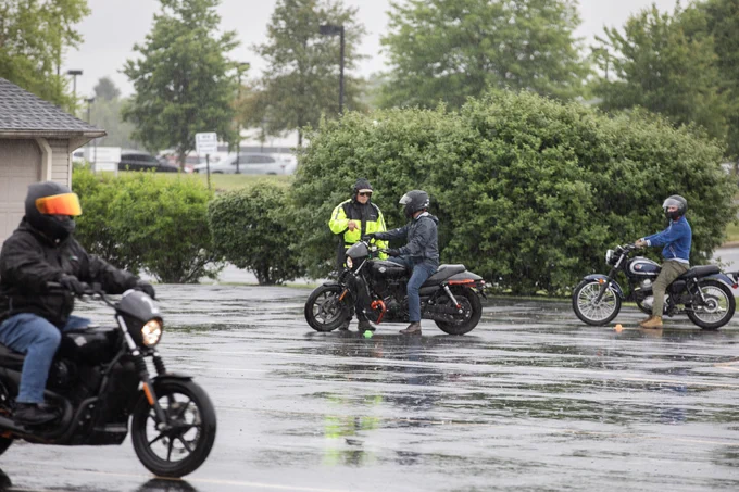 Motorcyclists ride around an outdoor course in the rain.