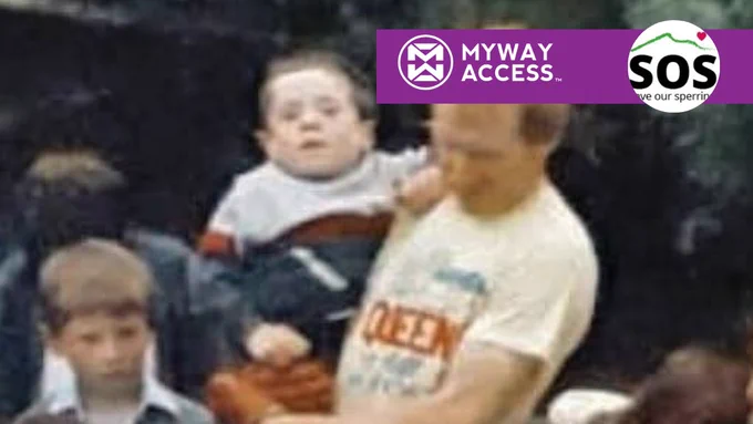 Oliver McCullagh in a light shirt is holding a young Dermot Devlin, with another child standing nearby. The upper right features purple and white MYWAY ACCESS and SOS logos. The background is on a home made water raft in a rural river.