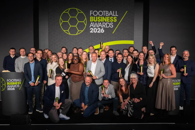 A celebratory group photo of award winners at the Football Business Awards 2026. The mood is joyful and professional, with attendees holding their awards proudly on stage.