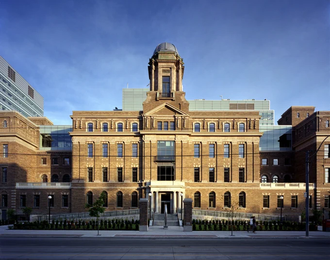 Historic brick building with a central tower and symmetrical windows under a clear blue sky.