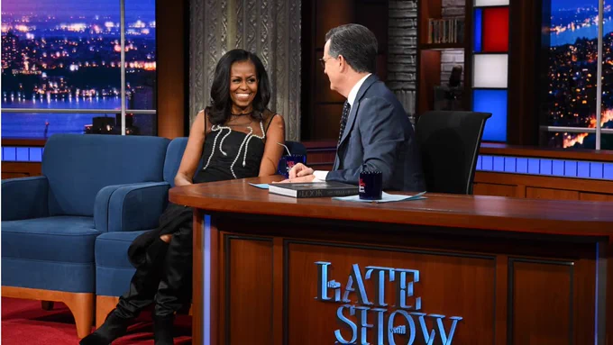 An image of Stephen Colbert interviewing a smiling Michelle Obama on "The Late Show."