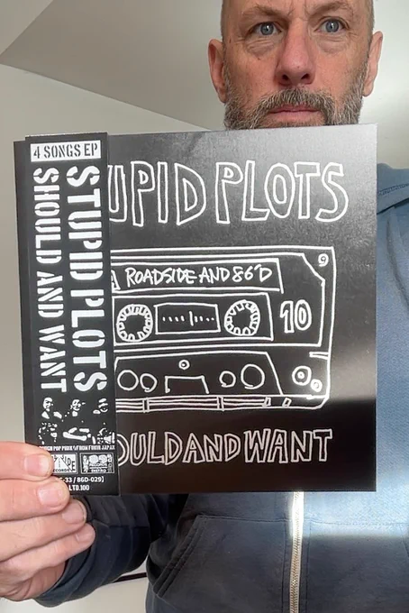 Man holding STUPID PLOTS 7" vinyl