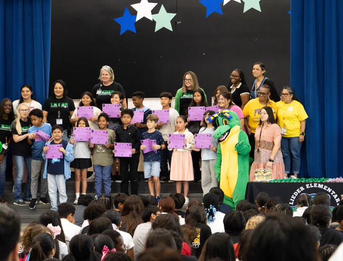 A group of students who just awards posing with Allie the Alligator mascot on stage.