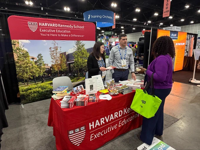 Dan Abar and Karen Morrissey at the Harvard Kennedy School Executive Education table at the 2026 ATD Conference, talking to a conference guest. 