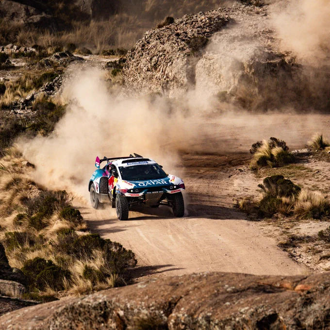 Prodrive Hunter rally raid car carving at high speed through Argentinian rocky terrain, dust trail hanging in the air on a winding dirt track