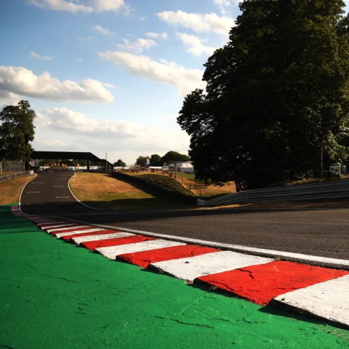 Red and white kerbs lining a smooth racing circuit, green runoff area leading into a fast sweeping corner
