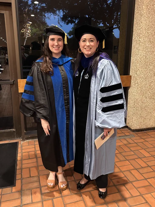 Two women smiling in academic regalia