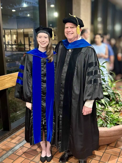 Woman and man smiling in academic regalia