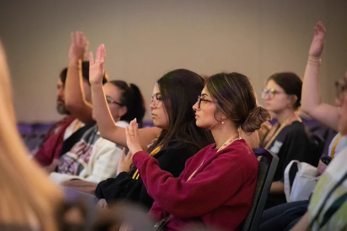 Photo of new students raising their hands.