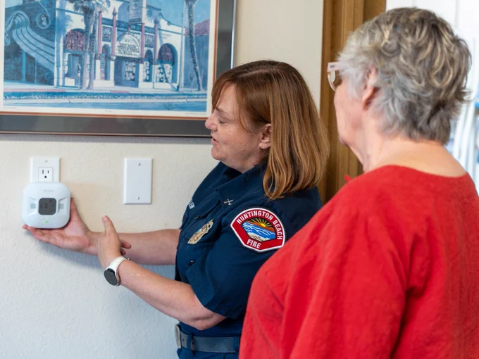 Huntington Beach Fire Marshal Janice Van Mullem speaks with a resident during a home safety visit while demonstrating the proper placement and operation of a carbon monoxide detector mounted on a wall inside the home. The visit is part of the Huntington Beach Fire Department’s free home safety program for qualifying residents.