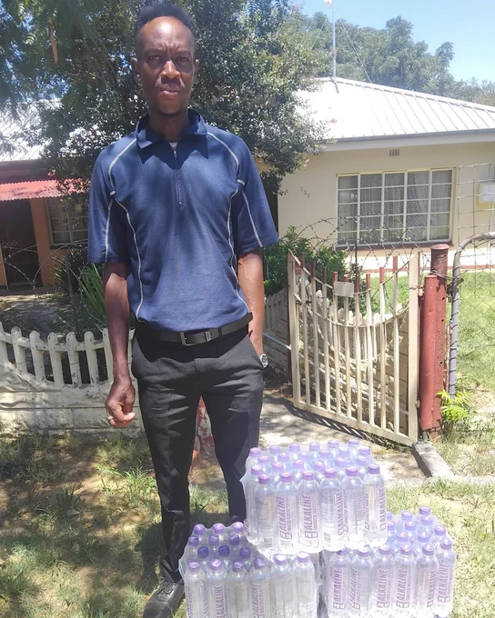 Phillimon, a new Waterpreneur stands next to cases of Designer Water pH10 in Kroonstad South Africa.