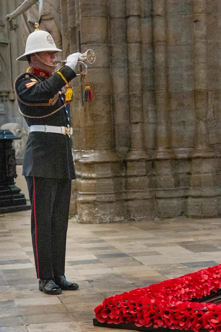 A bugler in military uniform standing beside the Grave of the Unknown Warrior in Westminster Abbey