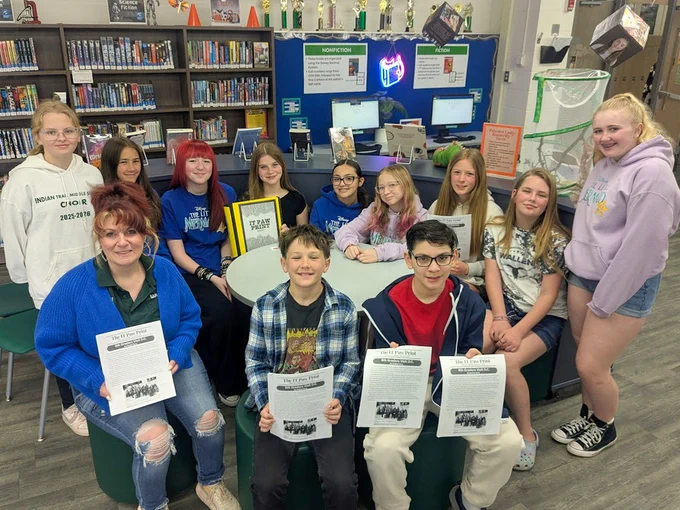 group of students, on adult hold up copies of Paw Print newspaper