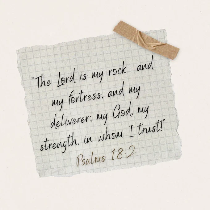 A handwritten religious quote from Psalms 18:2 on torn grid paper, taped to a surface. The mood is contemplative and spiritual.