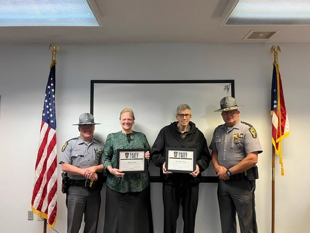 Lt. Westerfield and Trooper Cramer are pictured with Mary and Theodore Lyle (center) at the Wapakoneta Patrol Post. The Lyles are holding certificates for being Saved by the Belt. 