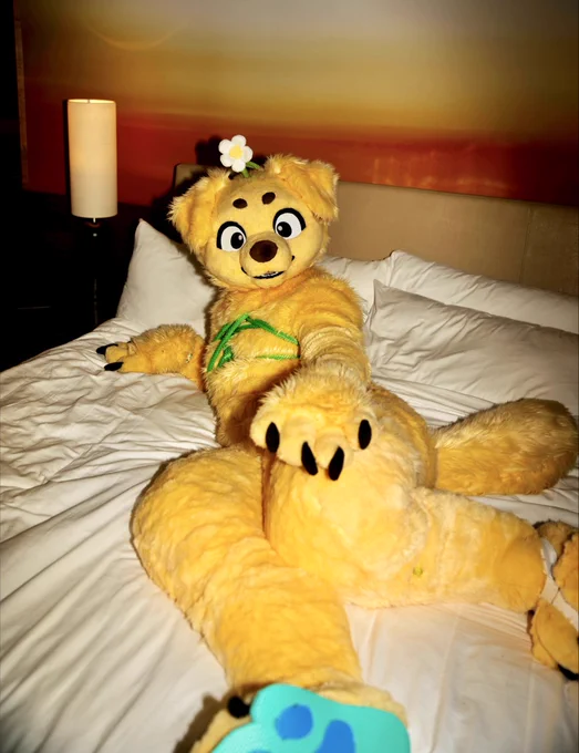 golden puppy fursuiter laying on a hotel bed looking at the camera, green shibari ropes around their torso