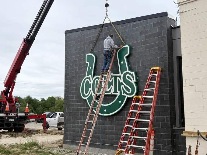 Man on ladder installing Colts sign