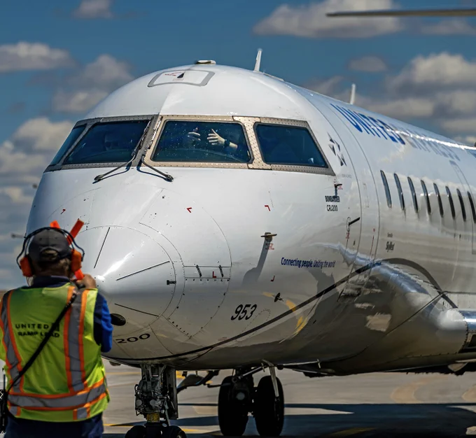A pilot gives two thumbs up in the window of an airplane after parking at the gate. 