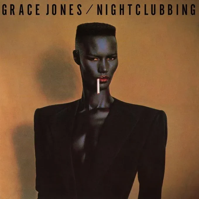 Copertina dell'album Nightclubbing di Grace Jones, con una foto a mezzobusto a Grace Jones stessa in giacca blu scura con spalle accentuate, senza niente sotto e una sigaretta in bocca. Sopra il titolo e il nome della cantante.