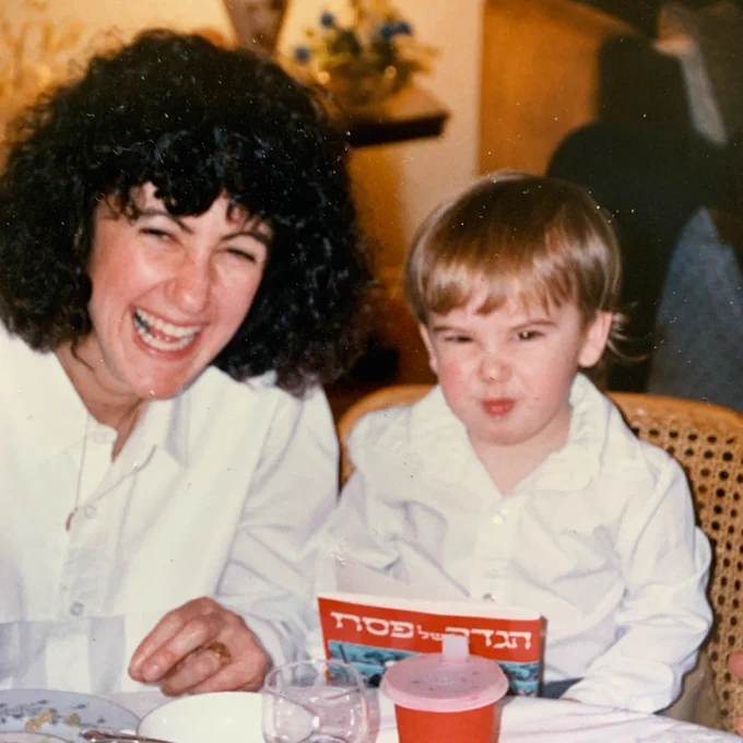 Me and my mom from my early year. We are both looking at the camera and smiling, while wearing white shirts.