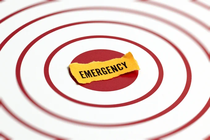 Yellow torn paper with 'EMERGENCY' text placed at the center of red concentric circles on a white background.