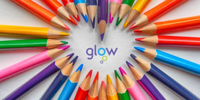Colourful sharpened pencils arranged in a heart pattern around the Glow logo on a white background.