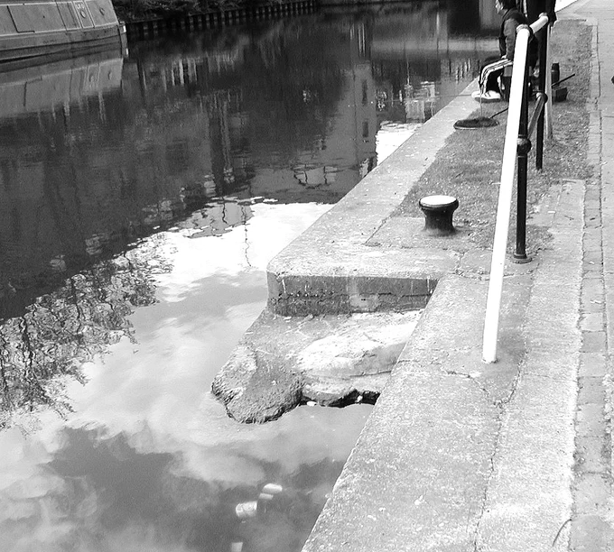 A monochrome photo of a brick ramp leading from the towpath into the canal water at Battlebridge Basin.
