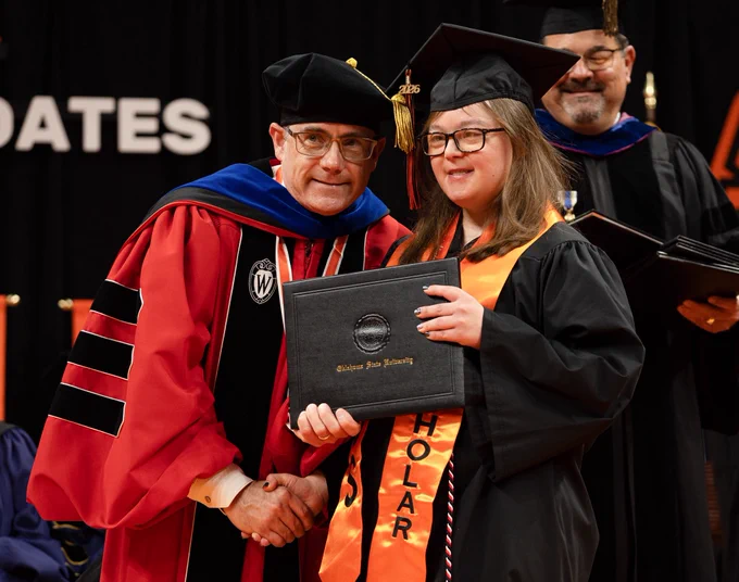 Dean Clarke and Opportunity Orange Scholar graduate shake hands.