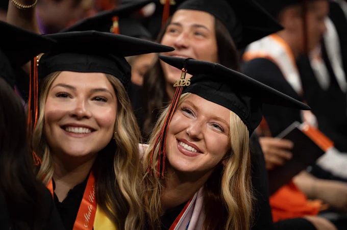 Two graduates smile up at the crowd.