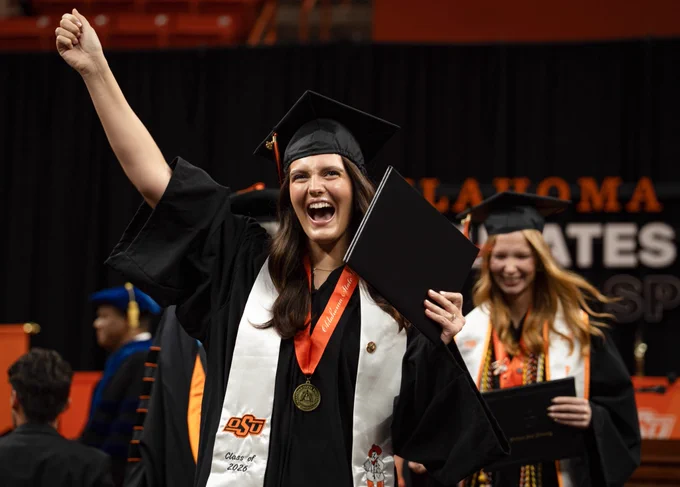 Graduate cheers with her diploma.