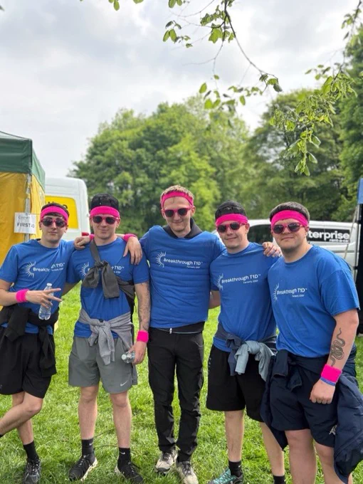 A group of people wearing blue Breakthrough T1D shirts standing together in a park.