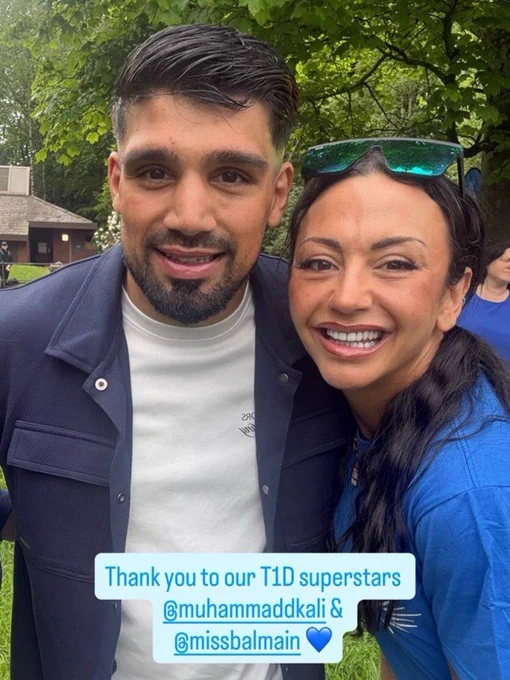 Two people standing together in a park during an outdoor community event.
