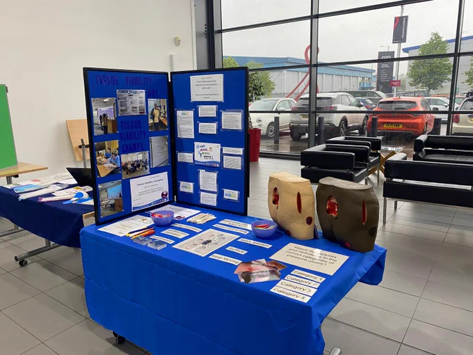 Tissue Viability Team conference stand featuring blue display boards, pressure ulcer training models, educational posters and resources focused on prevention and care.