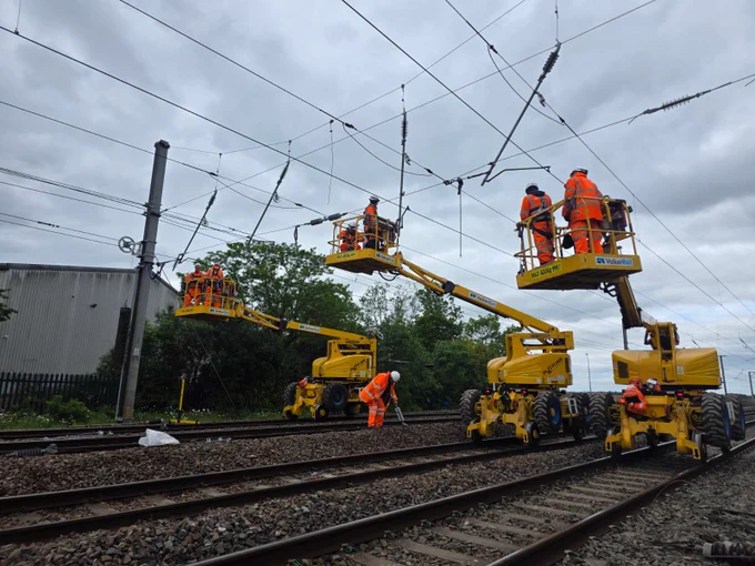 Cherry picker vehicles on track with workers in PPE working on overhead lines